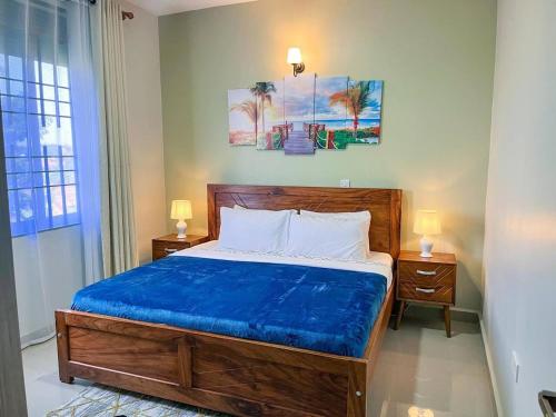 a bedroom with a wooden bed with a blue blanket at Cozy & tranquil 1 Bedroom dainty haven in Kampala in Buwate