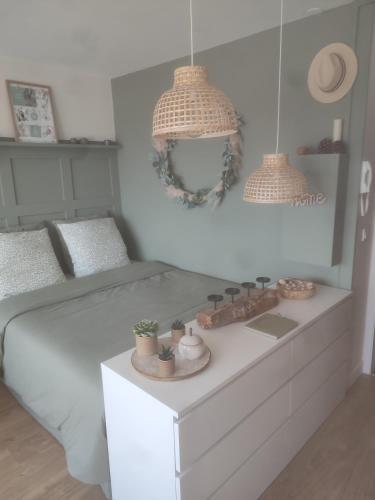 um quarto com uma cama branca e duas luzes pendentes em Appartement liberty em Courseulles-sur-Mer