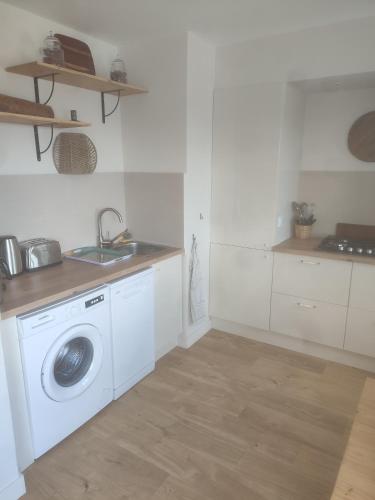 uma cozinha com uma máquina de lavar roupa e um lavatório em Appartement liberty em Courseulles-sur-Mer