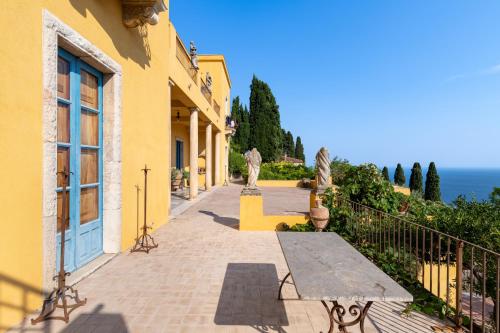 een geel gebouw met een bank op een stoep bij Casa Cuseni, Patrimonio Culturale Immateriale UNESCO in Taormina
