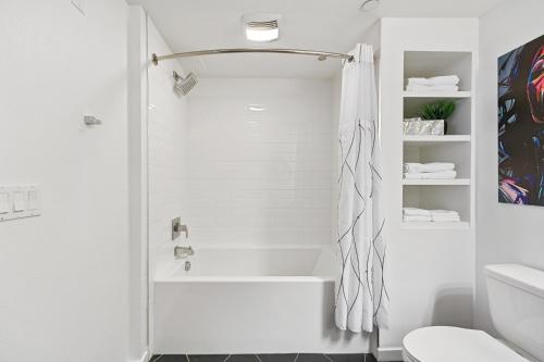 a white bathroom with a tub and a toilet at Fairfax District Chic City Oasis 2 BR Apt with Den 136 in Los Angeles