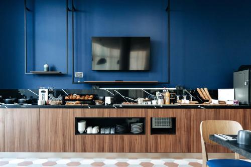 une cuisine aux murs bleus et une télévision sur un comptoir dans l'établissement Appart'City Collection Saint Germain en Laye, à Saint-Germain-en-Laye