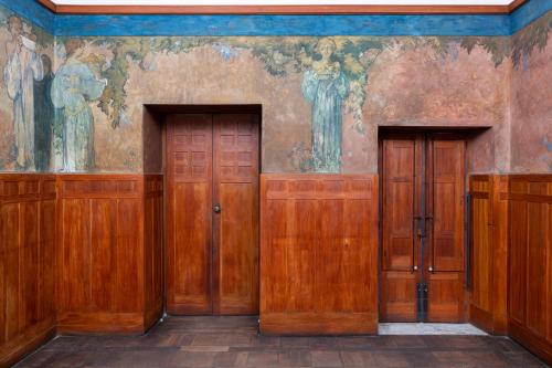 タオルミーナにあるCasa Cuseni, Patrimonio Culturale Immateriale UNESCOの壁画のある部屋の木製ドア2つ