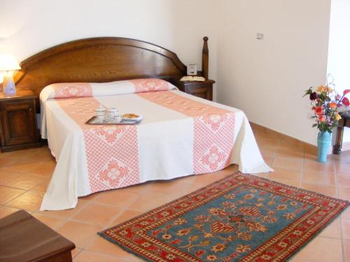 a bedroom with a bed with a table and a rug at Tenuta Su Vrau in Posada