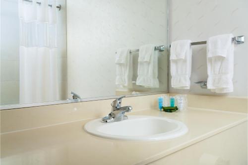 lavabo con espejo y toallas blancas en MCM Eleganté Hotel & Conference Center, en Beaumont