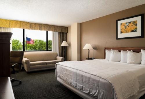 a hotel room with a large bed and a chair at MCM Eleganté Hotel & Conference Center in Beaumont