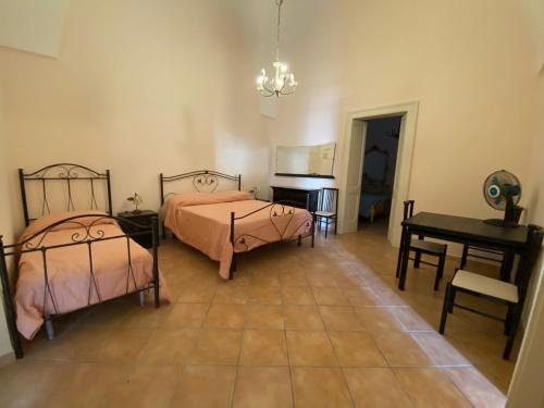 a bedroom with two beds and a table and a desk at Casa del Nonno Toto in San Pietro in Lama