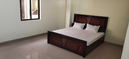 a bedroom with a large bed with a wooden headboard at SPOT ON 81358 Sun Shine Hotel in Jabalpur