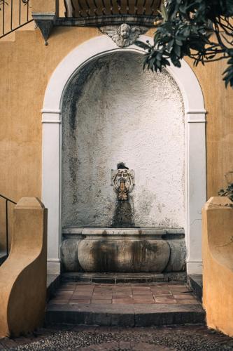 a fountain in front of a building with a statue at Casa Cuseni, Patrimonio Culturale Immateriale UNESCO in Taormina