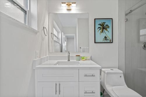 a bathroom with a sink and a toilet and a mirror at Immaculate, Private Home Near Ft. Lauderdale Beach in Fort Lauderdale