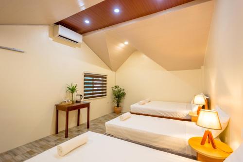 Habitación de hotel con 2 camas y mesa en ALONA BEACH SIDE INN en Panglao City