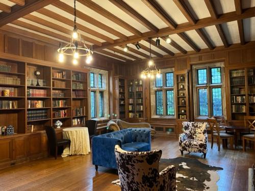 Habitación grande con biblioteca con sillas y libros. en The Castle at Skylands Manor en Ringwood