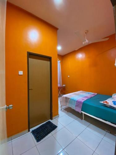 a bedroom with a bed and an orange wall at Pelangi Homestay 1 in Bachok