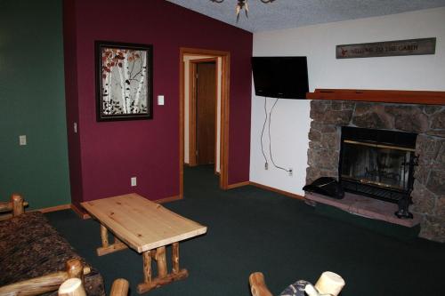a living room with a stone fireplace and a table at Timber Creek Chalets- 12 chalet in Estes Park
