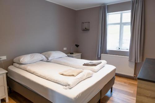 um quarto com uma cama com lençóis brancos e uma janela em Big house with a view em Akureyri