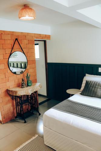 um quarto com uma cama e um espelho numa parede de tijolos em Studio Bougainville - Praia do Rosa em Imbituba