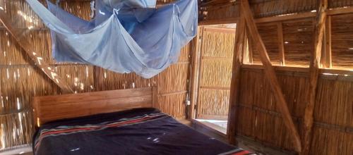 Bett in einem Holzzimmer mit einem Netz in der Unterkunft Povoado Bitonga in Inhambane