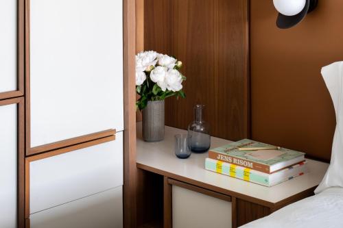 a table with books and a vase of flowers on it at Hotel Marcel New Haven, Tapestry Collection By Hilton in New Haven