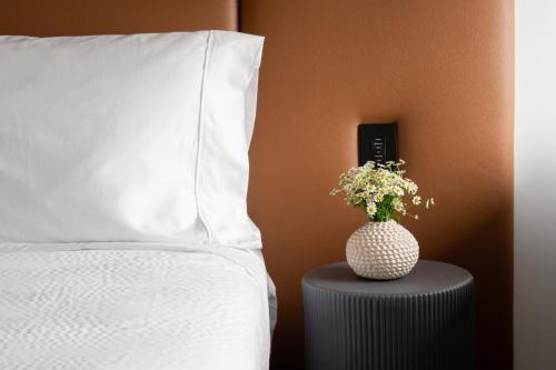 a bed with a pillow and a vase of flowers on a table at Hotel Marcel New Haven, Tapestry Collection By Hilton in New Haven
