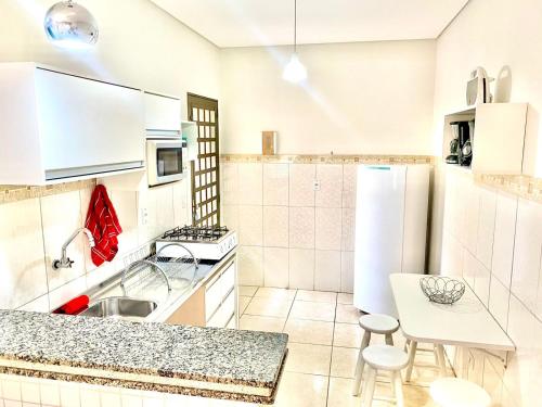 una cocina con electrodomésticos blancos, mesa y sillas en Vila Sinhá en Bonito