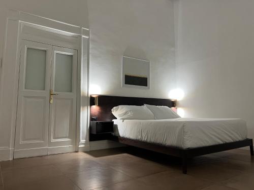 una camera da letto con un letto e una parete bianca di Domus Delia Luxury Apartment a Napoli