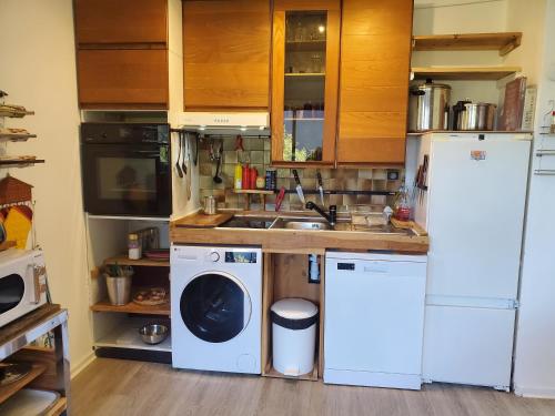 a kitchen with a white refrigerator and a washer and dryer at Appartement Col de l'Arzelier in Château-Bernard