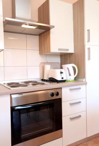 a kitchen with white cabinets and a stove top oven at Apartment Fila i Jure in Solin