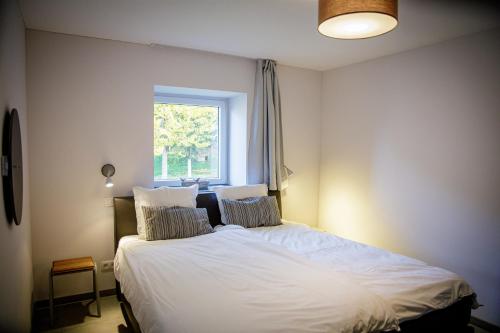 1 dormitorio con 1 cama blanca grande y ventana en Le gîte du Bois de Loo, en Attert