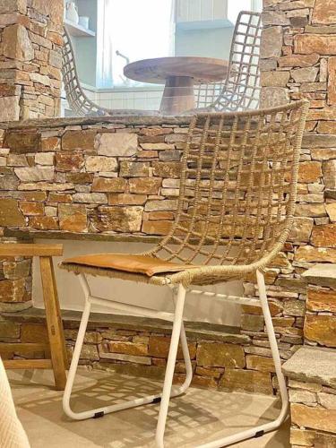 a wicker chair sitting in front of a stone wall at Dee House Sifnos in Sifnos