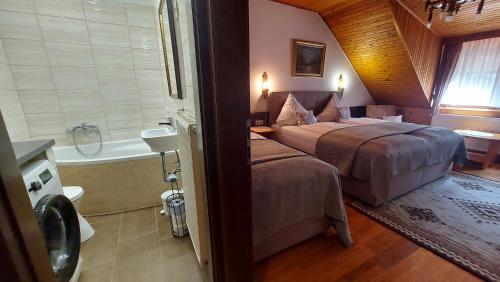 a bedroom with a bed and a bathroom with a tub at Titi Boutique Apartmanok in Bükfürdő