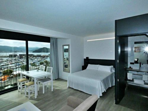 a hotel room with a bed and a table with a view at Apartamentos Dabarca Combarro in Combarro