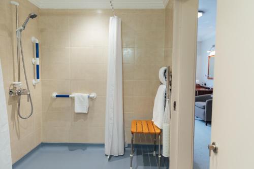 a shower with a shower curtain and a stool in a bathroom at The Woburn in Woburn