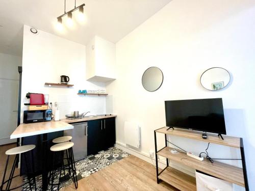 un salon avec une télévision et un comptoir avec des tabourets dans l'établissement Lodge Cassard, à Nantes