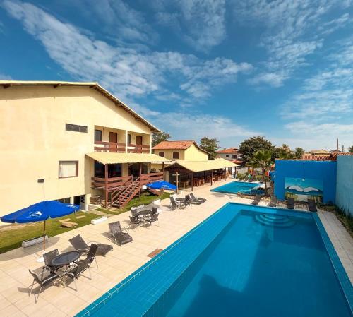 una piscina con sillas y sombrillas junto a un edificio en Pousada do Albatroz, en Cabo Frío