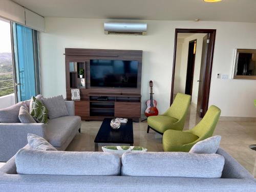 a living room with a couch and chairs and a tv at 14F Luxury Resort Lifestyle Ocean Views in Playa Bonita Village