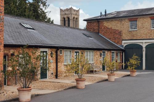 an old brick building with potted trees in front of it at The Woburn in Woburn