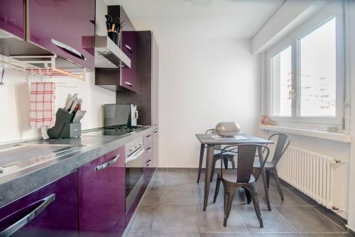 a kitchen with purple cabinets and a small table at Lugano Ferienwohnung nähe vom See mit Swimmingpool & Sauna in Paradiso