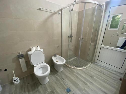 a bathroom with a toilet and a glass shower at Guest House Sherifi Berat in Berat