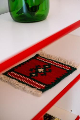 a red rug on a white shelf with a green vase at Guesthouse Rose in Sarajevo