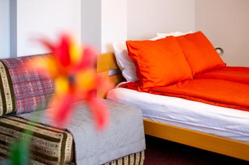 a bedroom with a bed and a couch with orange pillows at Guesthouse Rose in Sarajevo