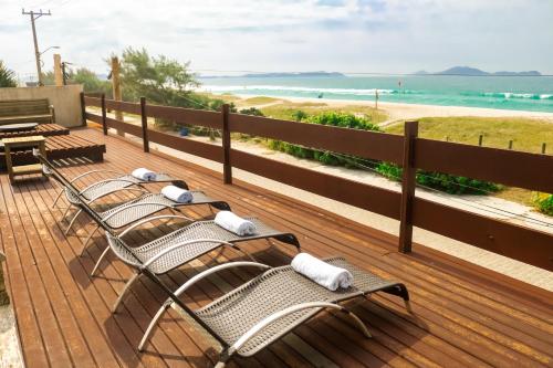 - une rangée de chaises assises sur une terrasse avec la plage dans l'établissement Pousada do Albatroz, à Cabo Frio