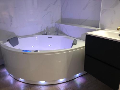 La salle de bains est pourvue d'une baignoire blanche et d'un lavabo. dans l'établissement Suite Bubbles Spa - Luxe - Centre Ville - calme - wifi, à Troyes