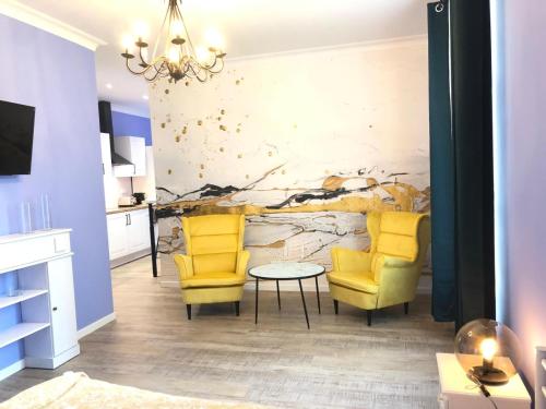 salon z 2 żółtymi krzesłami i stołem w obiekcie Suite Bubbles Spa - Luxe - Centre Ville - calme - wifi w Troyes
