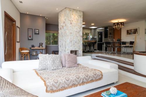 uma sala de estar com um sofá branco e uma lareira em Casa com Jacuzzi Vista Mar no Campeche P2299 em Florianópolis