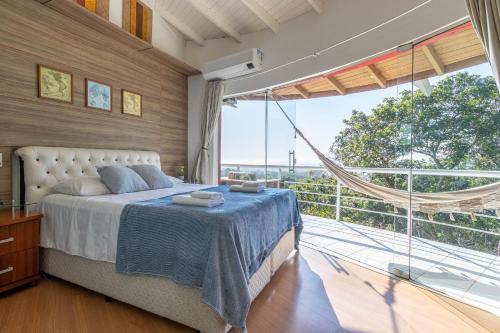 ein Schlafzimmer mit einem Bett und einem großen Fenster in der Unterkunft Casa com Jacuzzi Vista Mar no Campeche P2299 in Florianópolis