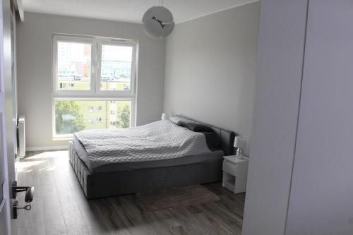 - une chambre blanche avec un lit et une fenêtre dans l'établissement Baltea Apartament Gdańsk Przymorze, à Gdańsk