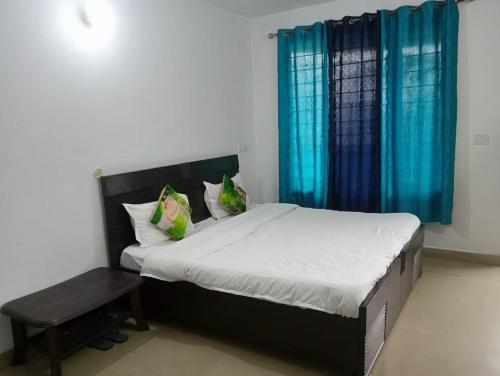 een slaapkamer met een groot bed en blauwe gordijnen bij SANDAL HOMESTAY in Kasauli