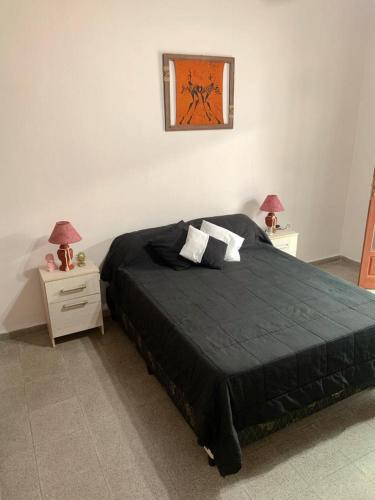 a bedroom with a large black bed with two night stands at Departamento VILLA NUEVA in Villa María