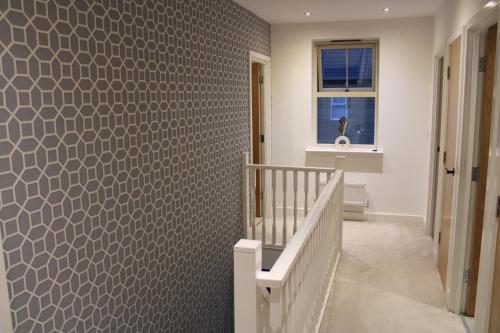 a hallway with a staircase with a patterned wall at Haven - Spacious Luxury Home perfect for families, couples and contractors! 5mins to Xscape and Junction 32! in Castleford