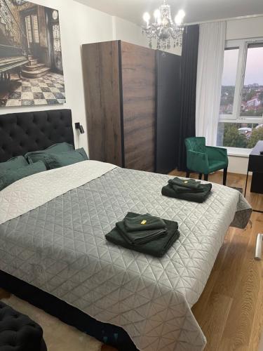 a bedroom with a bed with two black towels on it at Plaza extra lux apartman garage free in Stanovo
